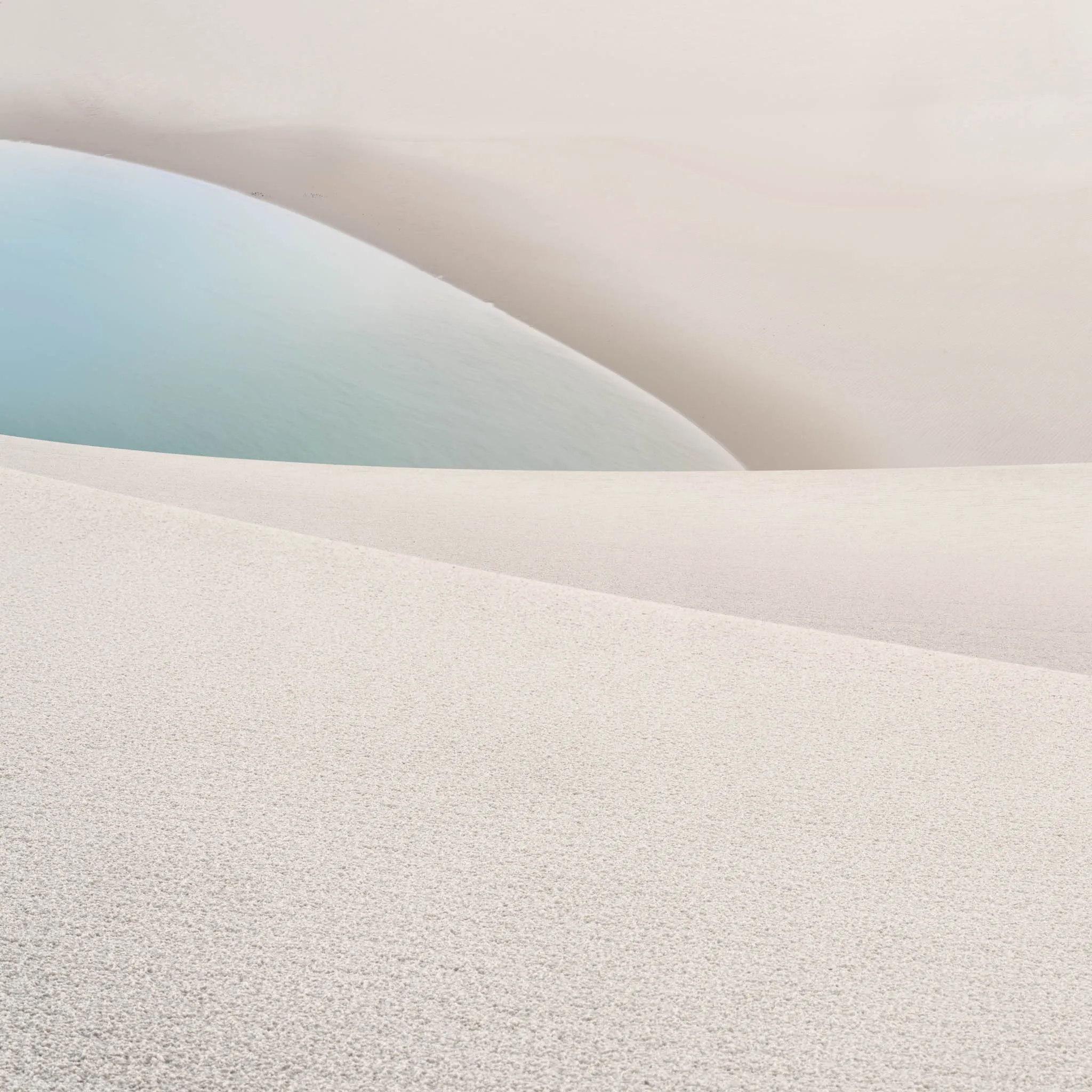Layered white dune crests cradling a soft turquoise lagoon between them
